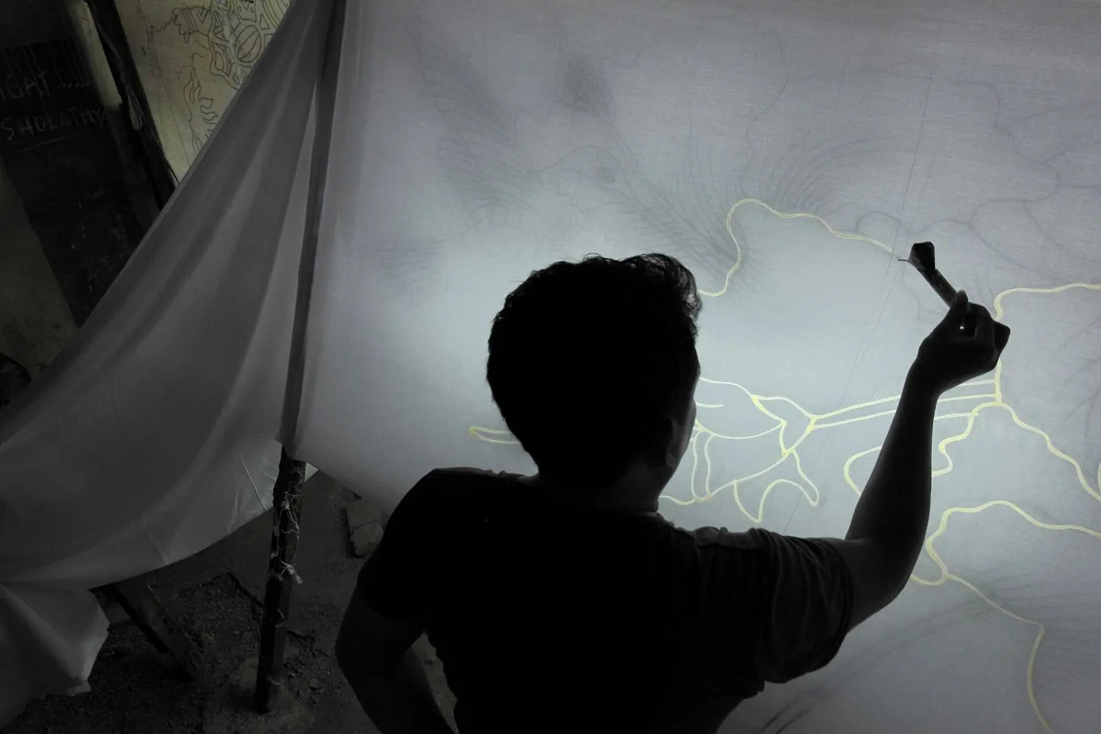 A batik artist drawing wax lines on cloth